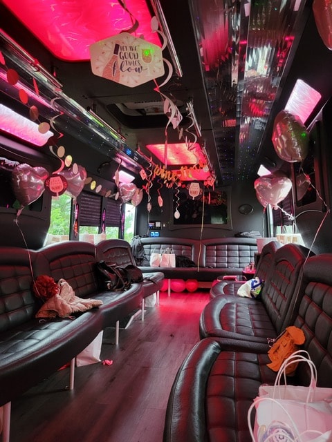 Party bus interior decorated with pink balloons and neon lighting